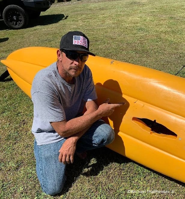 Thallheimer pointing to white shark bites in his kayak.